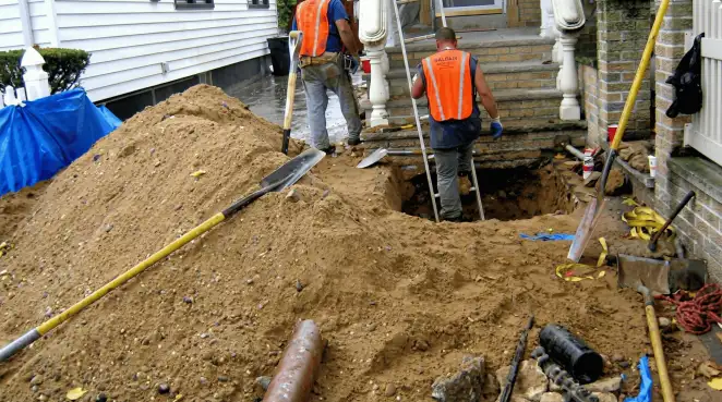 Contractors performing foundation protection and exterior drainage excavation near residential home steps in Fresno, CA